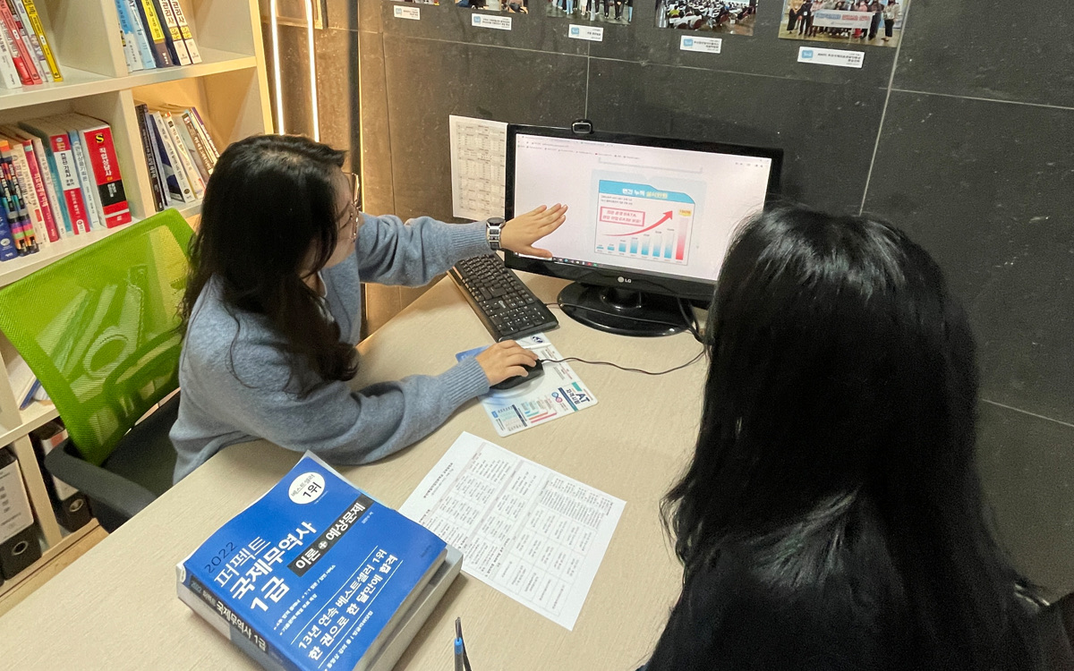 부산예일직업전문학교 직업상담사가 모니터와 직업상담사 교재를 활용해 훈련생과 상담하는 모습