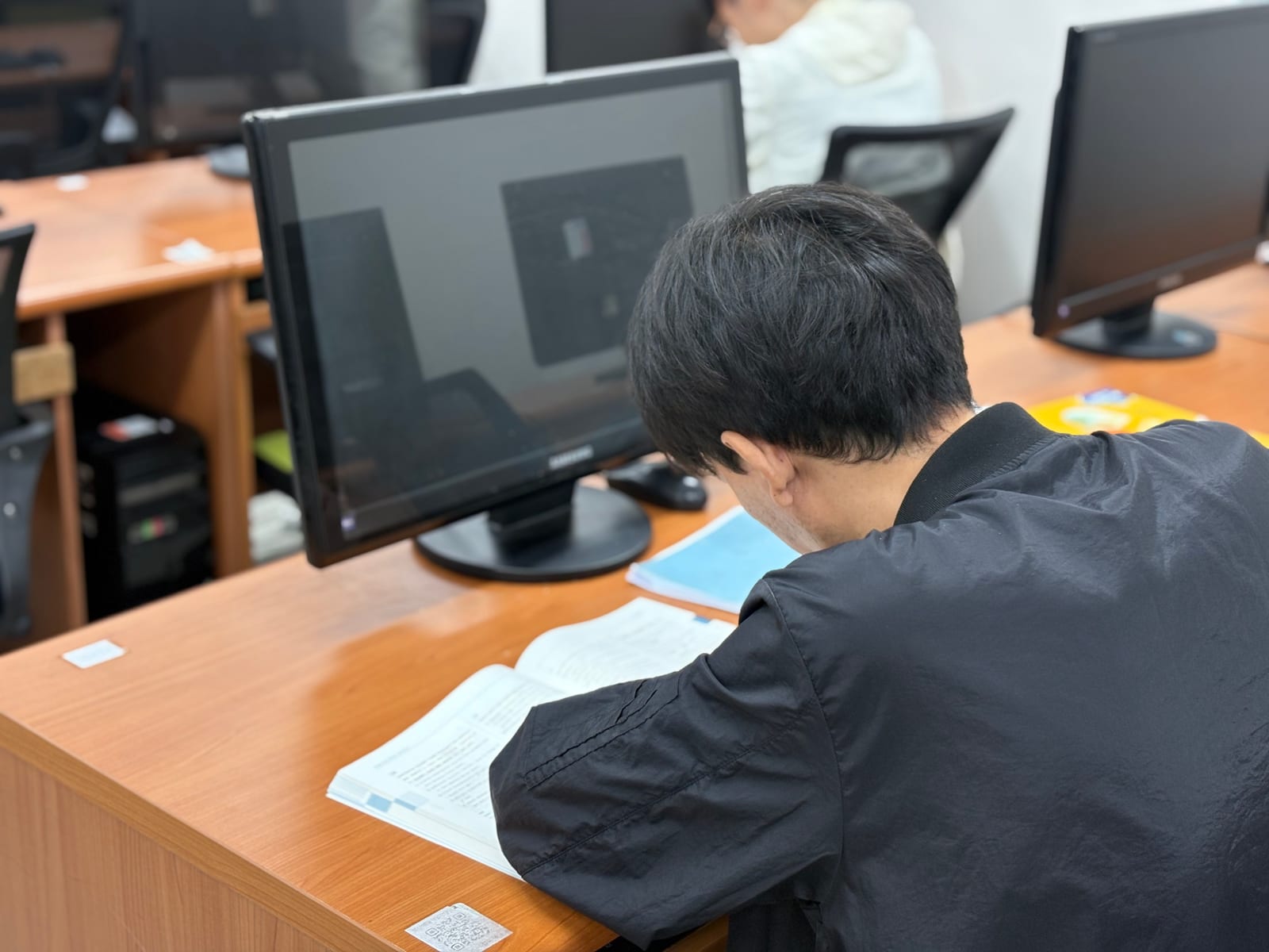 부산예일직업전문학교 훈련생이 교재와 컴퓨터를 활용해 무역물류 실무를 학습하는 모습